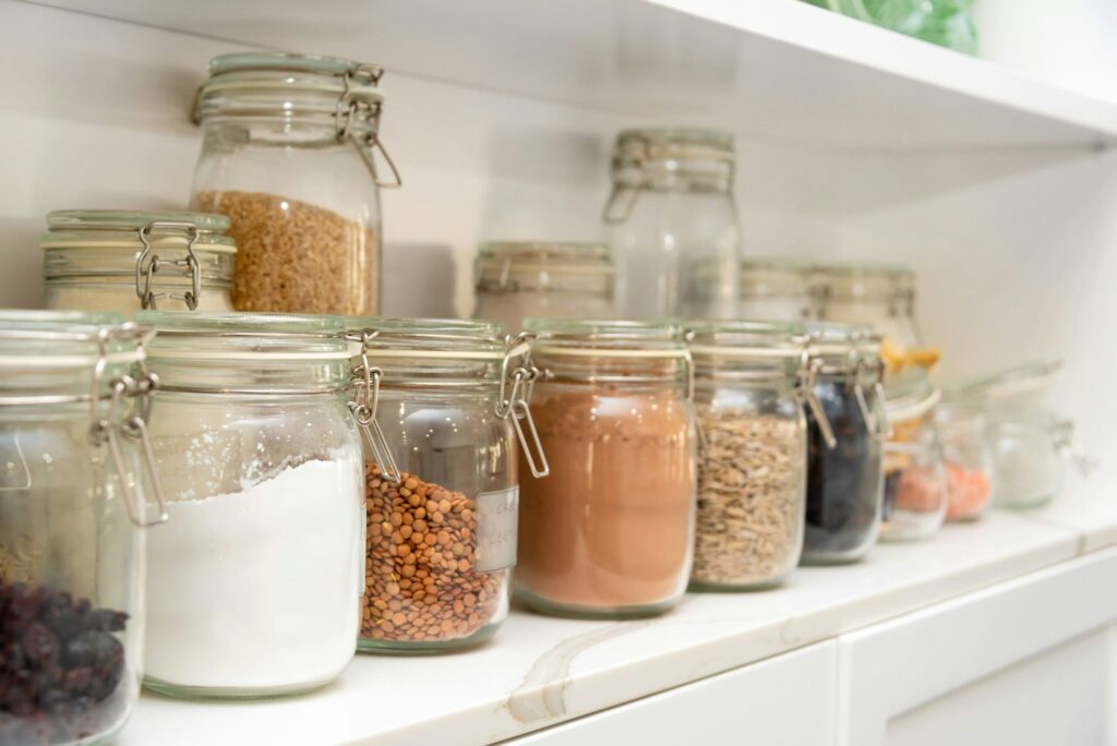 clear mason jars filled with pasta, spices, flour and other budget-friendly pantry essentials