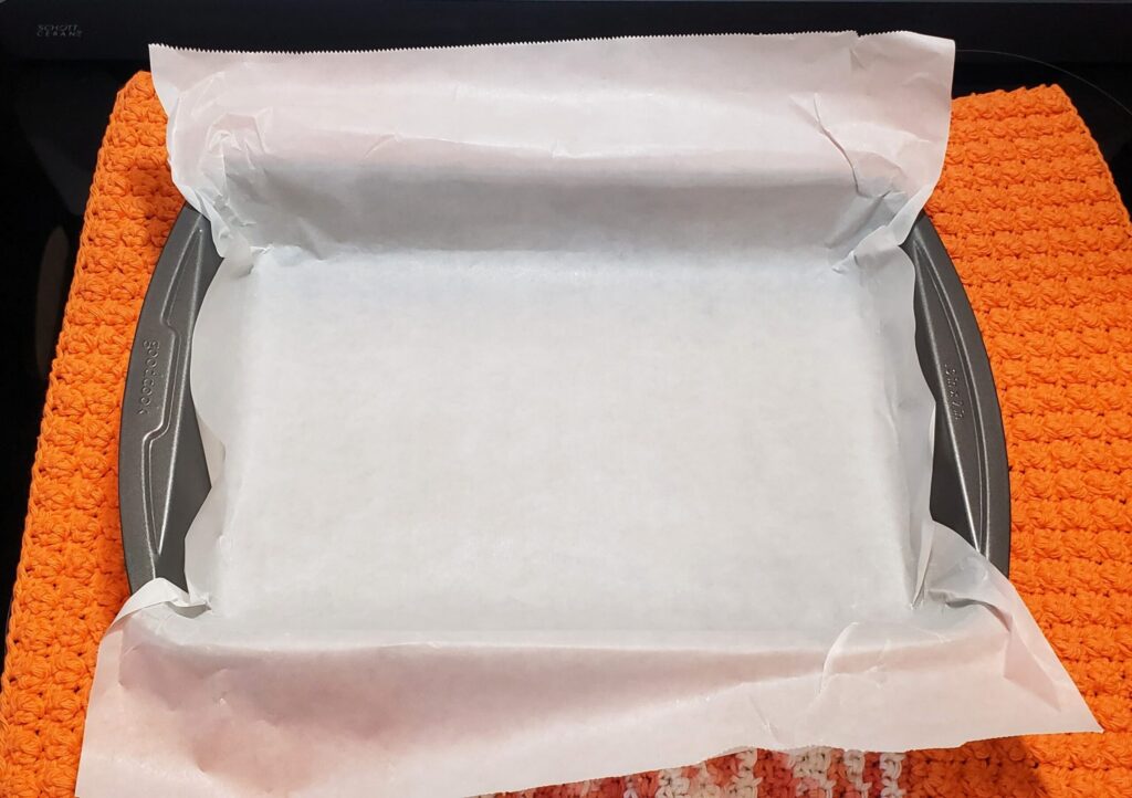 9x13 baking pan lined with parchment paper, ready for making pumpkin pie bars